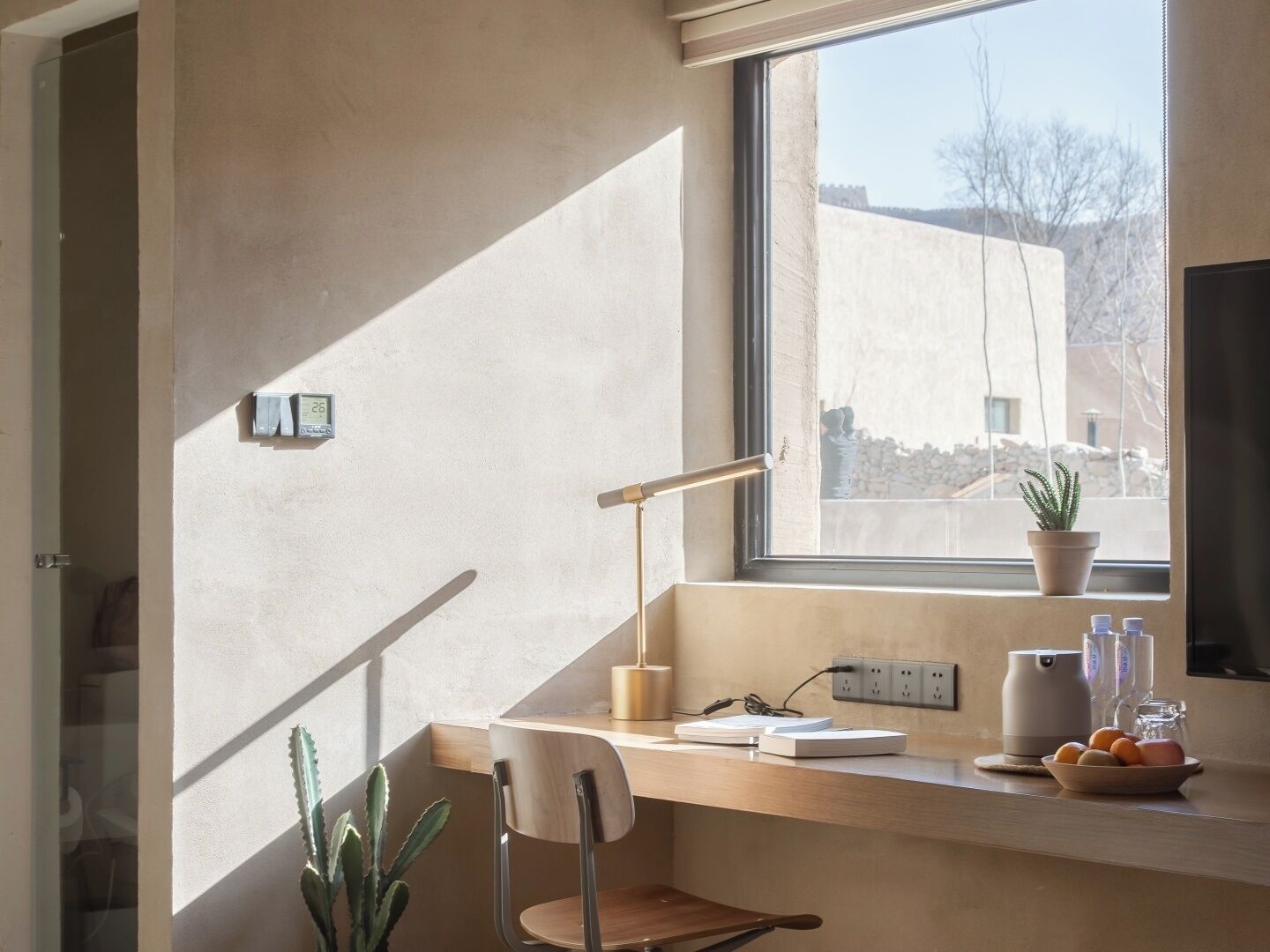 Ein moderner Arbeitsraum mit Schreibtisch, Stuhl und Fenster mit Blick auf ein Gebäude.