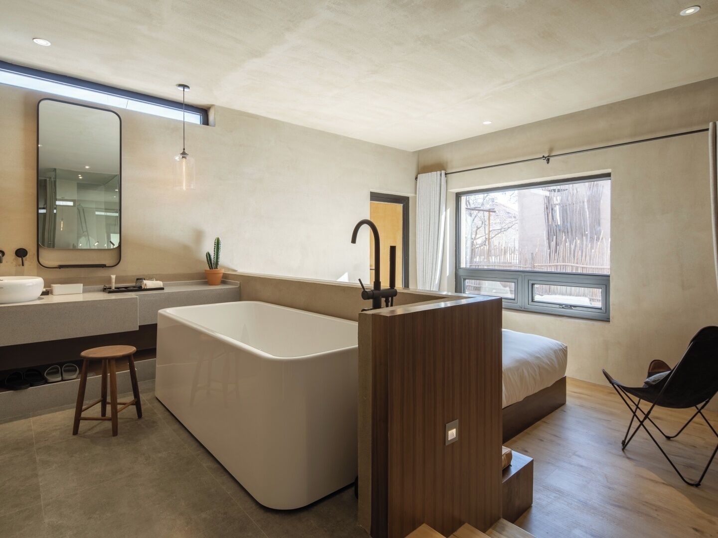 Un baño moderno con una bañera independiente, un espejo grande y un ventanal con vistas al exterior.