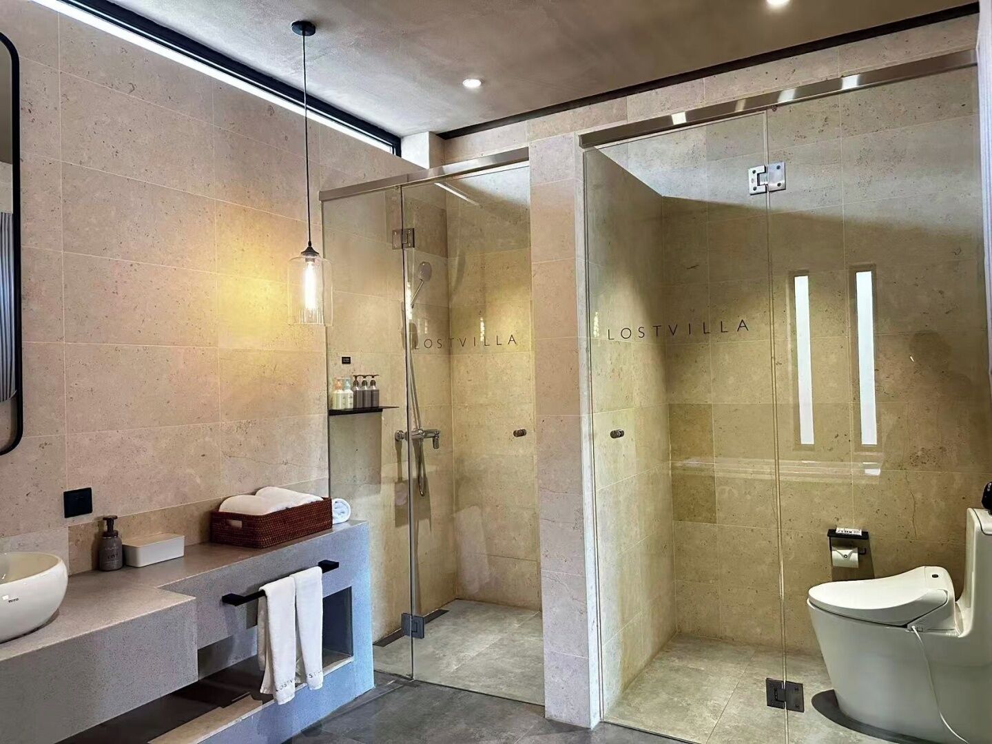 Un baño moderno con cabina de ducha de vidrio, un lavabo blanco y un mueble de tocador con toallero.