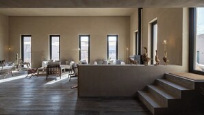 Amplia sala de estar con una isla central, ventanas grandes y una escalera que conduce a un nivel superior.