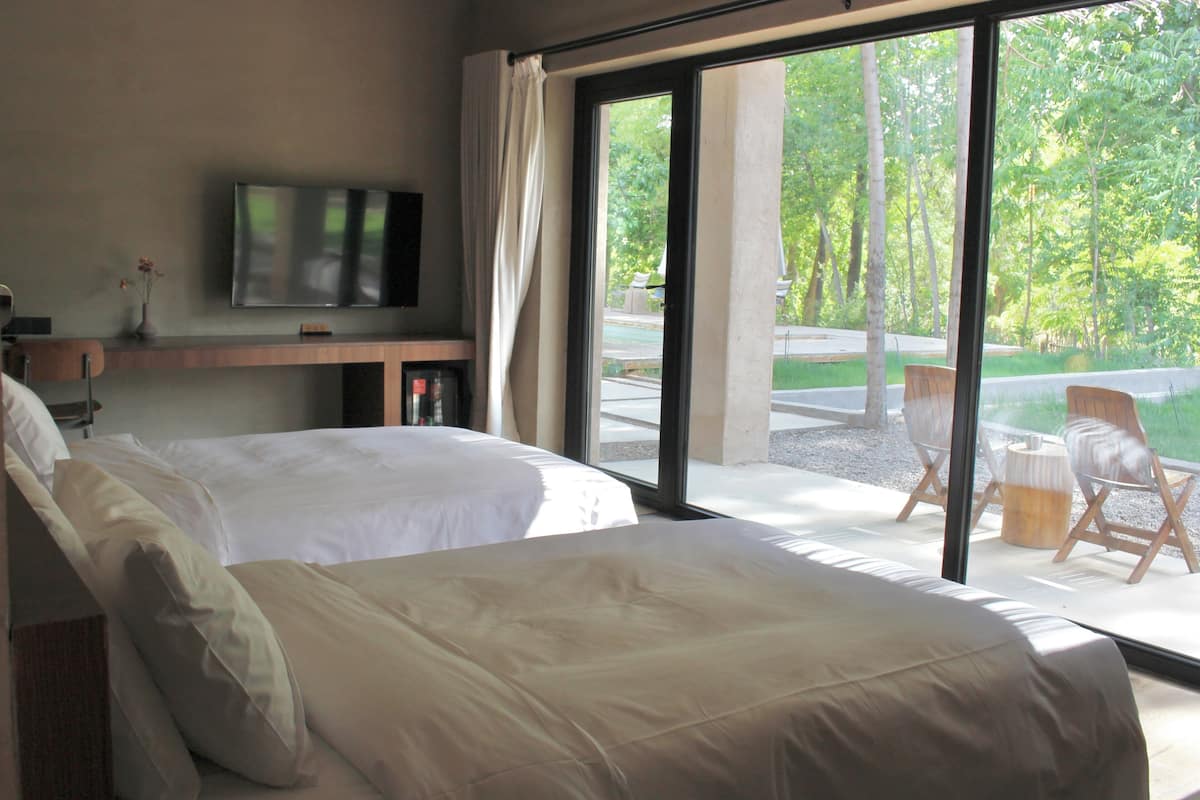 Une chambre d’hôtel avec deux lits, une télévision, un bureau et une vue sur l’extérieur.