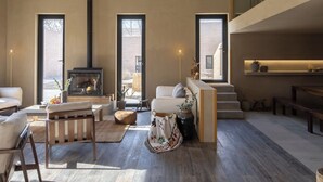 Amplia sala de estar con chimenea, ventanas grandes, ventilador de techo y una cocina moderna.