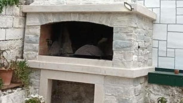 A stone-built outdoor oven with a chimney, surrounded by potted plants and a stone wall. - Apartments Anna Biograd na Moru (Biograd na Moru)