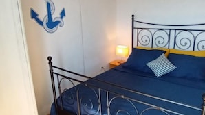 A bed with a metal frame, a blue bedspread, and a striped pillow. - Apartments Anna Biograd na Moru (Biograd na Moru)