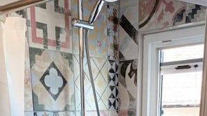 A shower with a handheld showerhead, a glass door, and a tiled wall with geometric patterns. - Apartments Anna Biograd na Moru (Biograd na Moru)