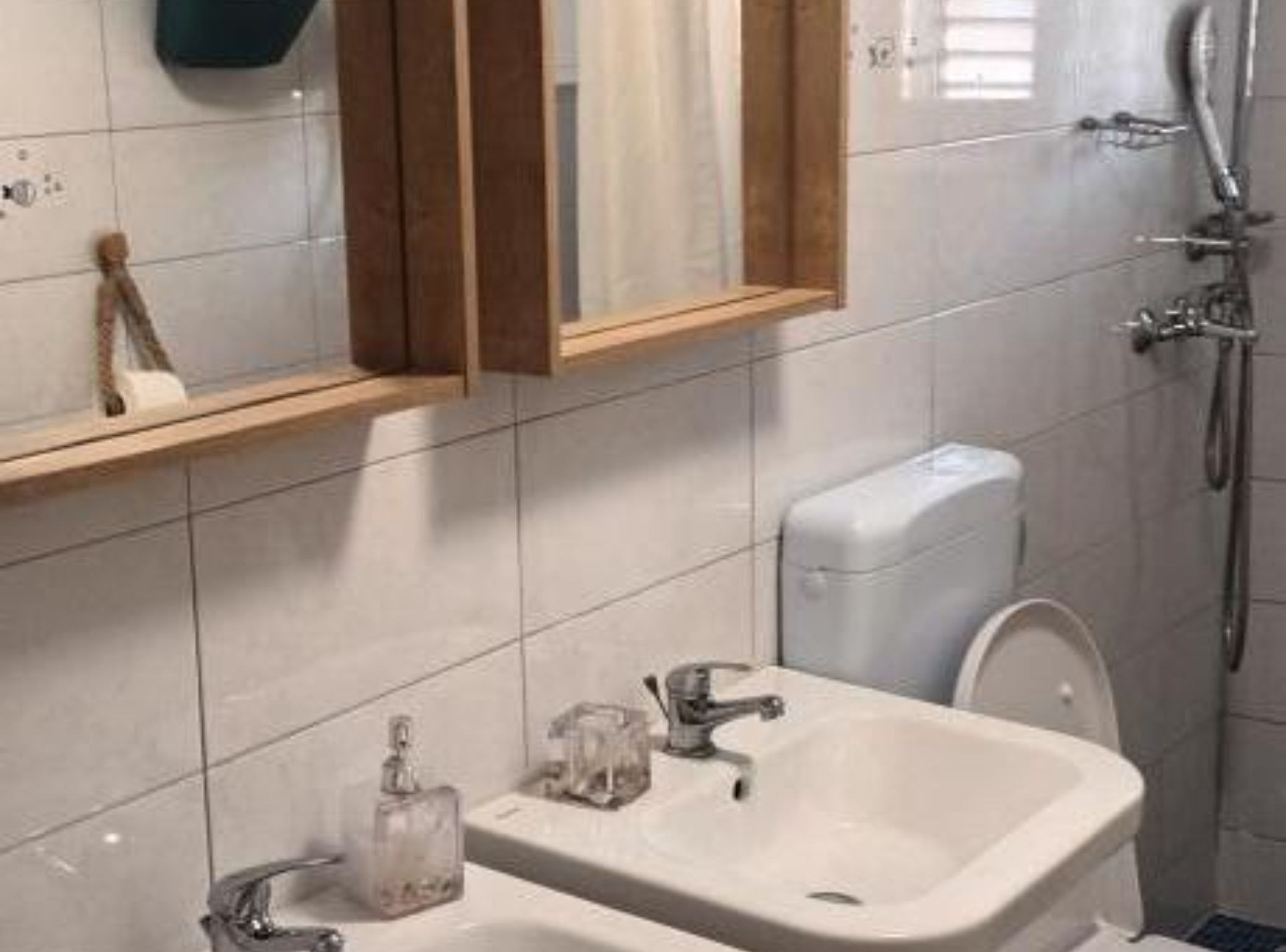A bathroom with a white sink, a mirror, a toilet, and a shower.