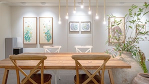 A dining area with a wooden table and chairs, artwork on the walls, and hanging lights. - Denbasta Hotel Guseo (Busan)