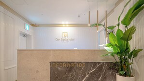 A reception area with a marble counter labeled "INFORMATION" and a sign for "Den Basta hotel." - Denbasta Hotel Guseo (Busan)