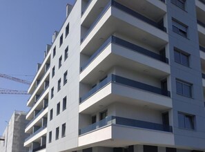 Um edifício com vários andares, varandas, janelas amplas e um design arquitetônico moderno.