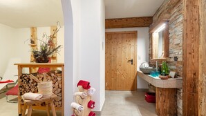 Una habitación acogedora con un banco de madera, un perchero y una mesita con una planta.