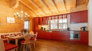Interior de madera con comedor, cocina y ventana con vistas.