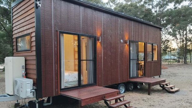 Une petite cabane en bois d’un seul étage, dotée de grandes fenêtres, d’une porte coulissante et d’un petit espace porche.