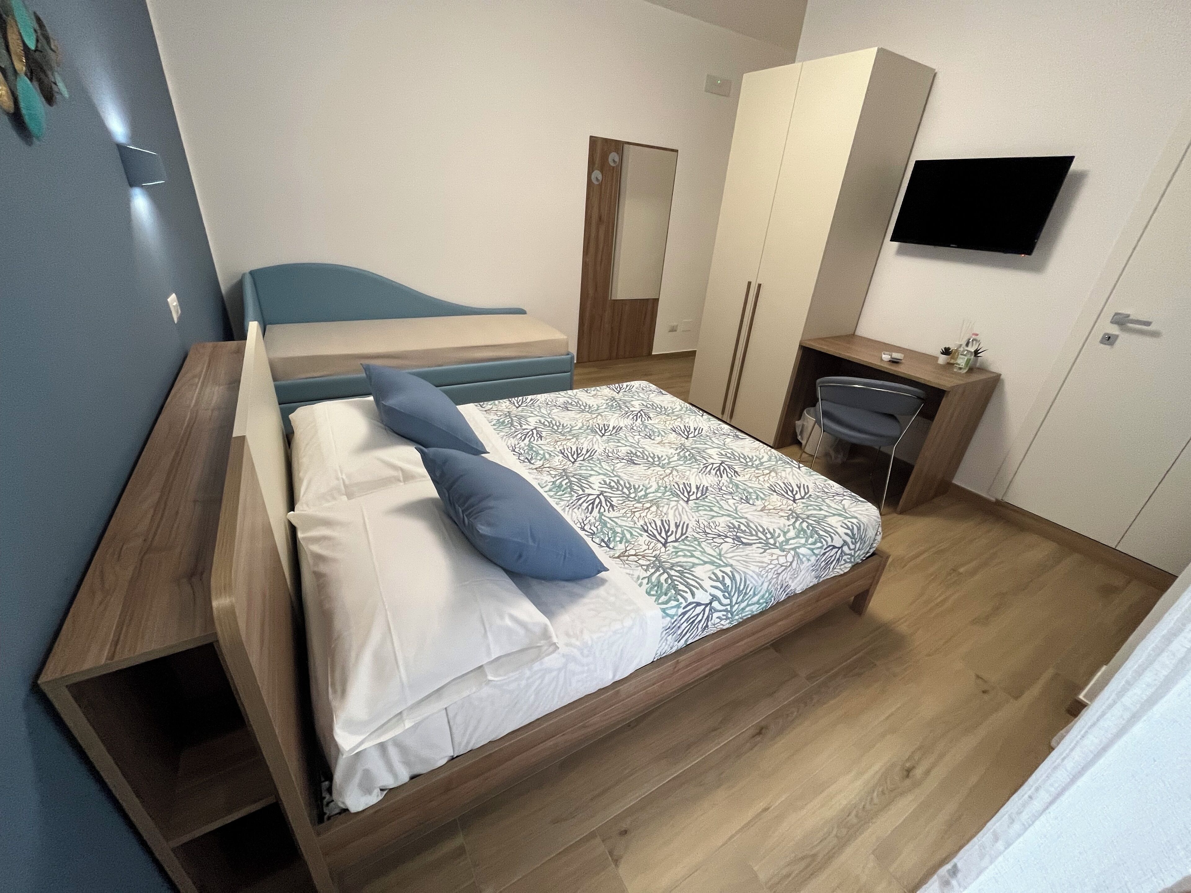 Una camera da letto moderna con un letto di legno, una scrivania e un armadio.