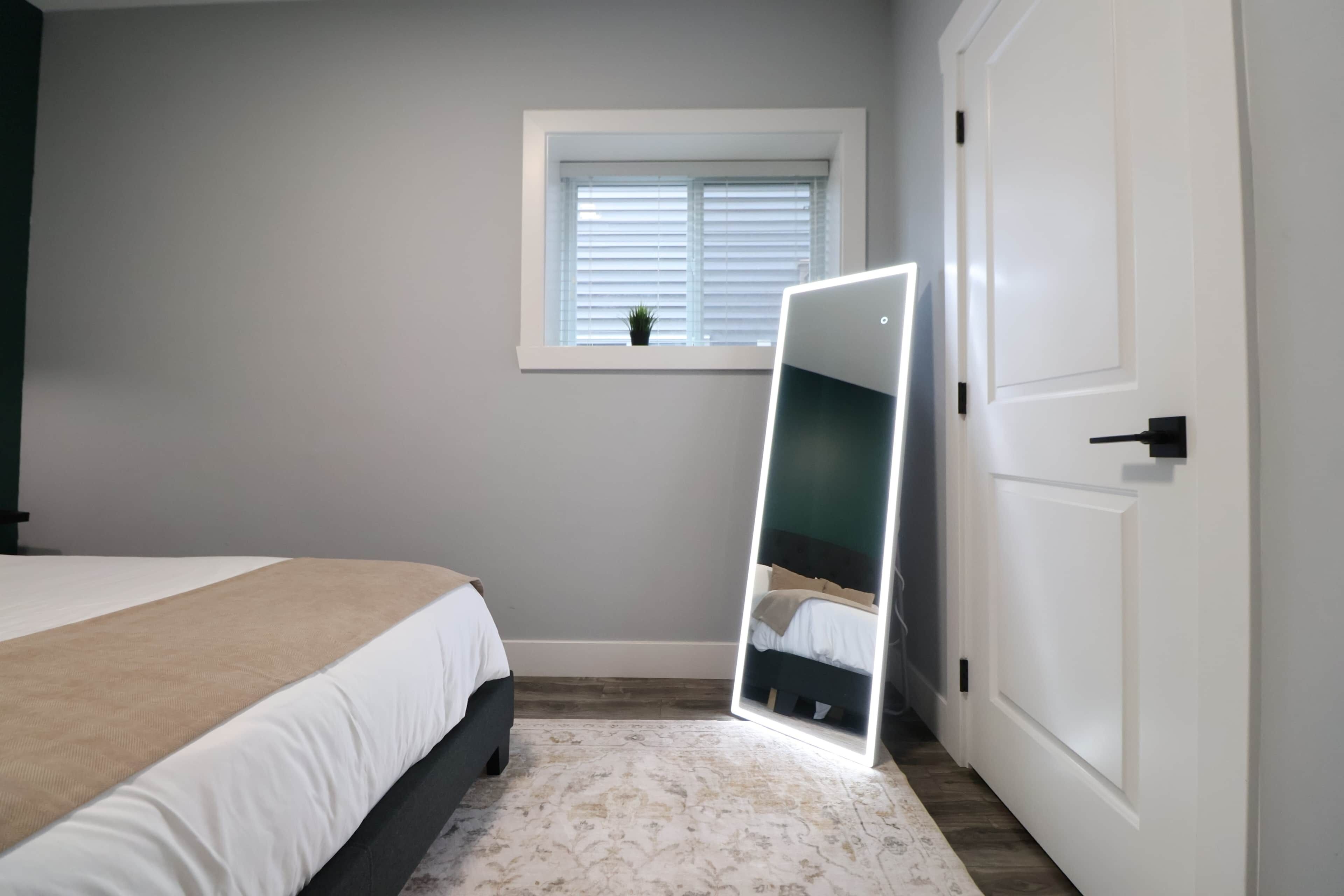 Ein Schlafzimmer mit einem Bett, einem Fenster mit Jalousien, einem Spiegel und einer Tür.