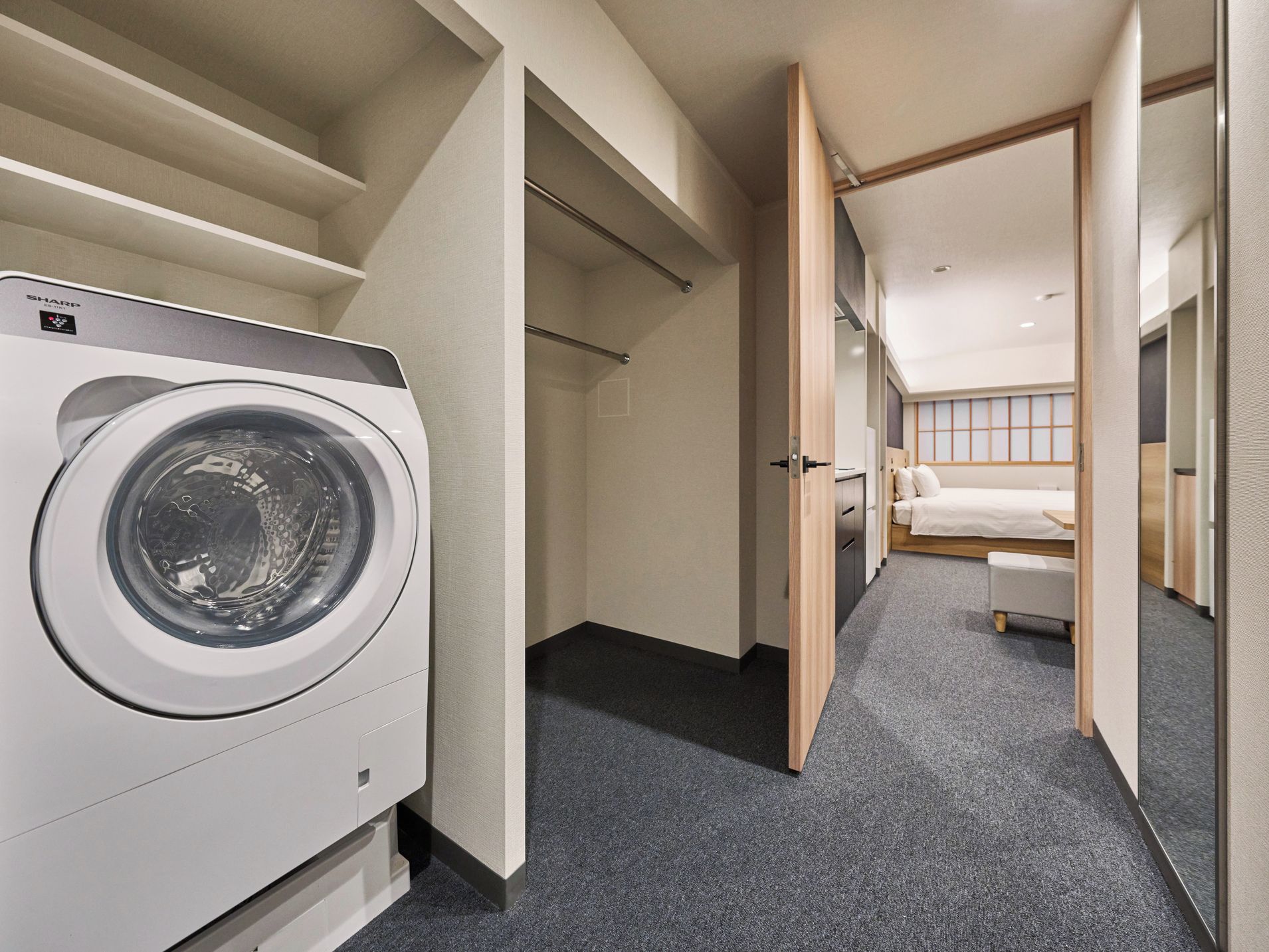 A hotel room with a washing machine, a bed, and a bathroom.