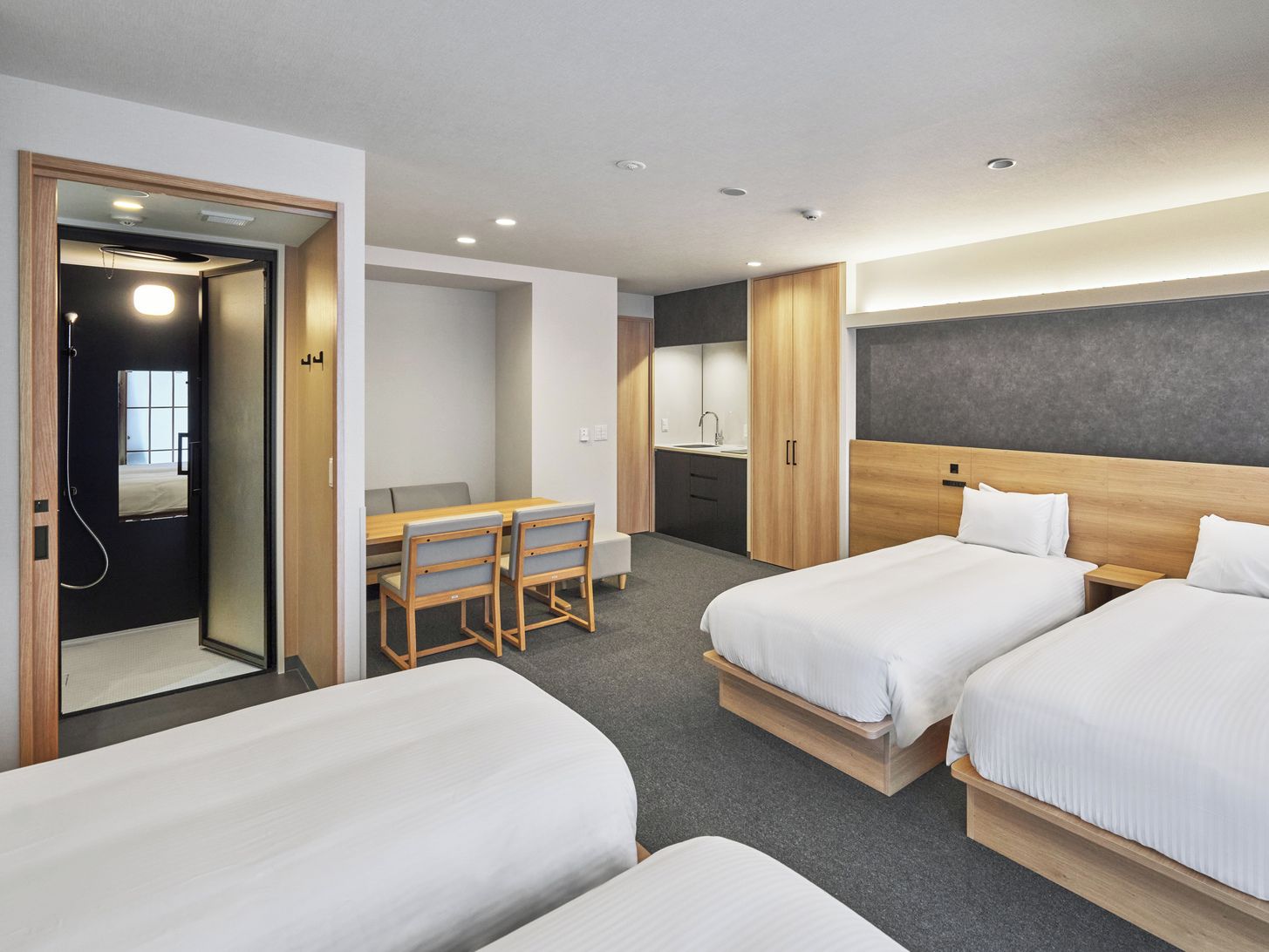 Une chambre d’hôtel avec deux lits, un bureau et une petite kitchenette.