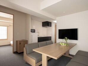 A modern, compact living space with a kitchenette, a dining area with a table and bench, and a TV mounted on the wall. - MIMARU Osaka Namba Station Annex (Opens on October 1, 2026) (Osaka)