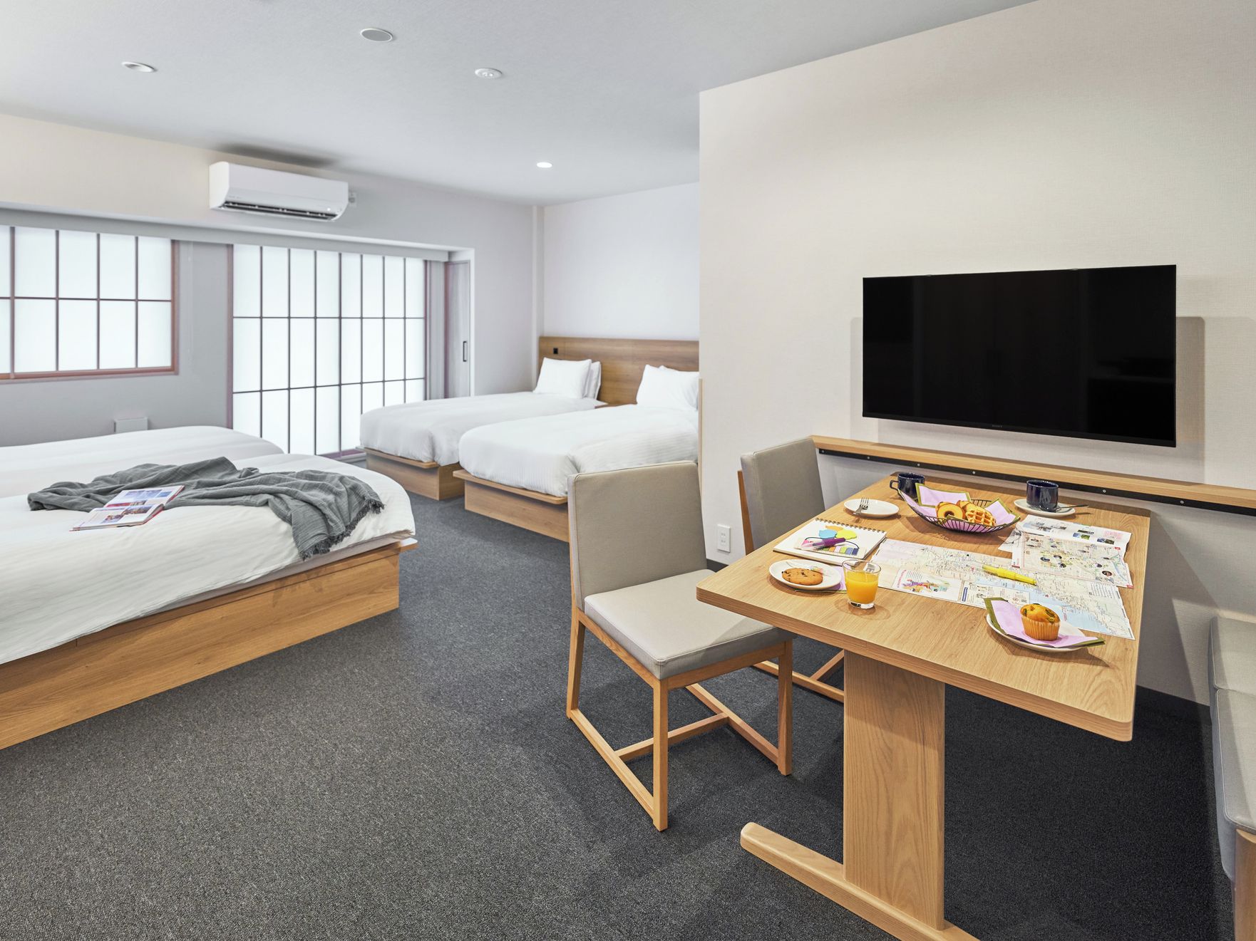Une chambre d’hôtel avec deux lits, un bureau avec des articles pour le petit-déjeuner, une télévision et un appareil de climatisation.