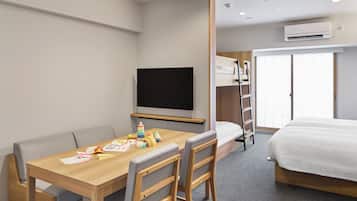 A hotel room with a wooden desk, a television, a bunk bed, and an air conditioning unit.