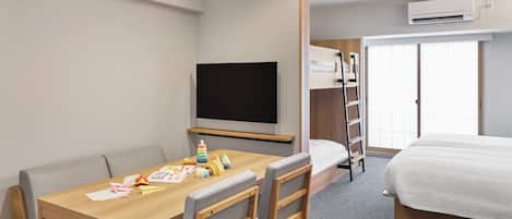 Una habitación de hotel con un escritorio de madera, televisión, literas y un aire acondicionado.