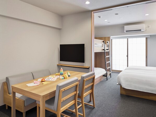 Une chambre d’hôtel avec un bureau en bois, une télévision, un lit superposé et un appareil de climatisation.