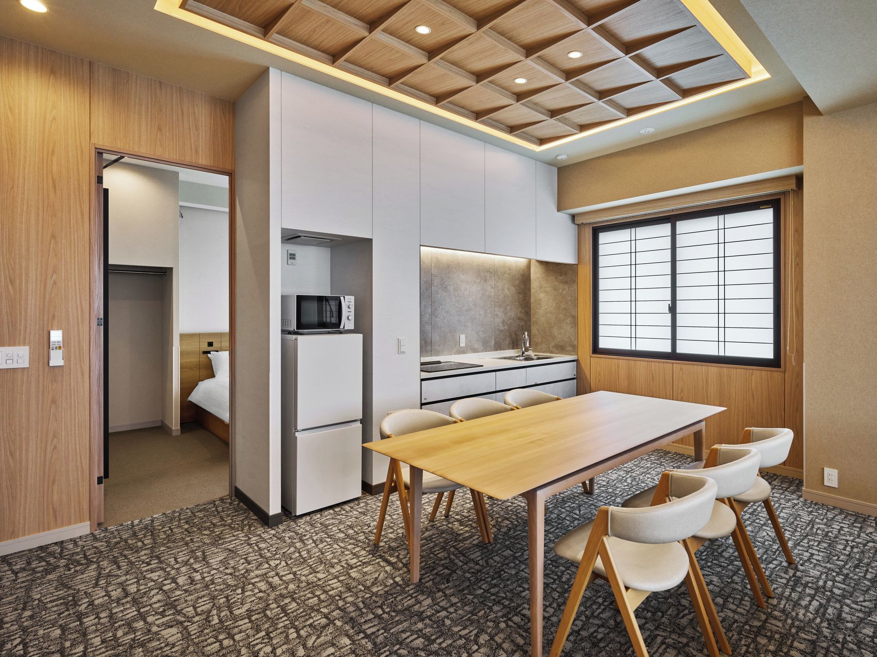 Une chambre d’hôtel compacte dotée d’une kitchenette, d’un coin repas et d’une grande fenêtre.