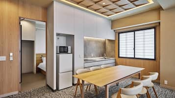 A compact hotel room with a kitchenette, a dining area, and a large window.
