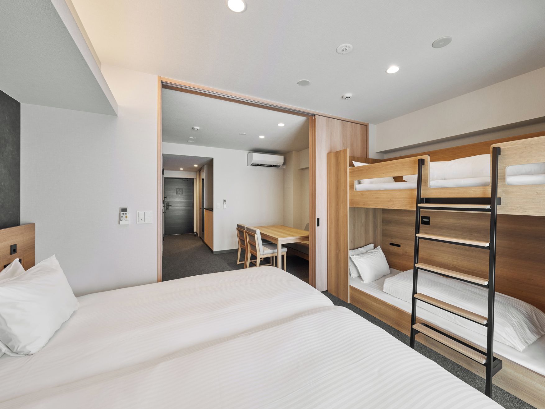 A modern hotel room with a bunk bed, a desk, and a chair.