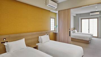 Une chambre d’hôtel avec deux lits, une tête de lit en bois, une fenêtre donnant sur un beau paysage et un appareil de climatisation.