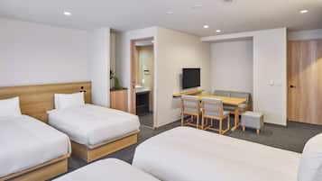 A hotel room with two beds, a desk, a chair, a television, and a door.