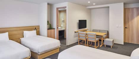 A hotel room with two beds, a desk, a chair, a television, and a door.
