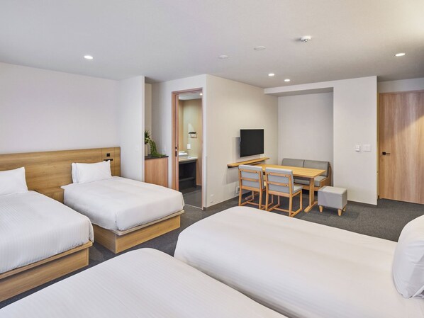 A hotel room with two beds, a desk, a chair, a television, and a door.