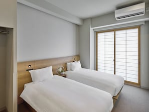 A hotel room with two beds, a wooden headboard, an air conditioning unit, and a sliding door with a grid pattern.