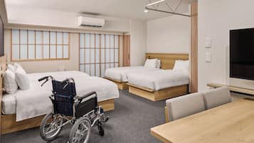 A hotel room with two beds, a wheelchair, a TV, and a dining table.