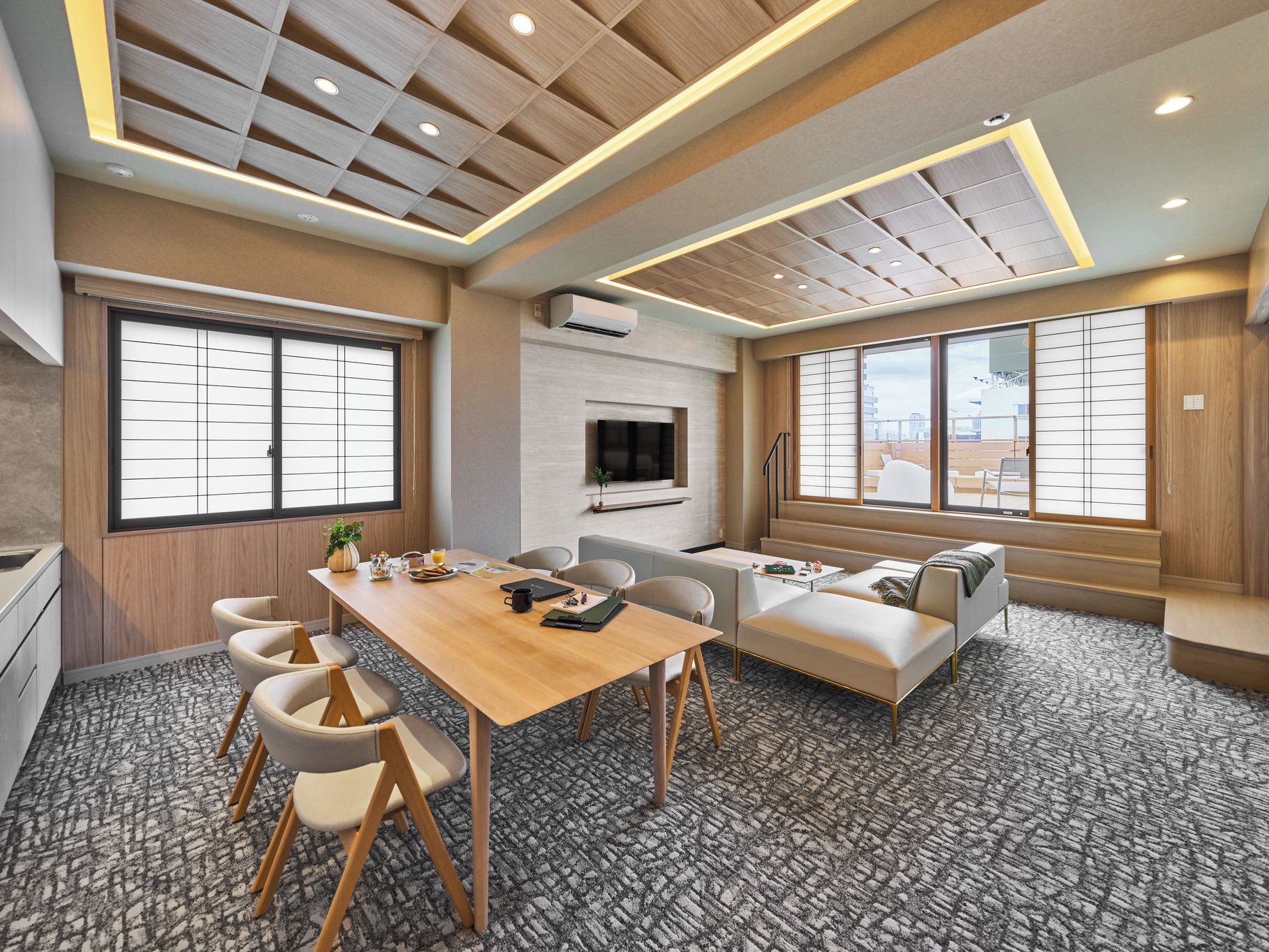 A modern hotel room with a wooden ceiling, a dining area with a table and chairs, a sofa, and large windows.