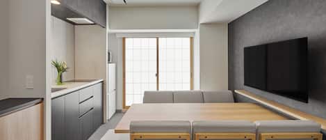 Una cocina moderna con comedor, televisor de pantalla plana en la pared y puerta corrediza que da a una habitación luminosa.