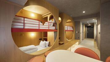 A modern hotel room with bunk beds, a round table, and a seating area.