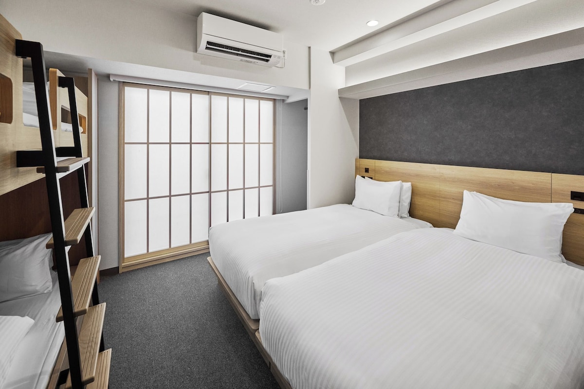 Une chambre d’hôtel avec deux lits, une armoire, une fenêtre donnant sur un beau paysage et un appareil de climatisation.