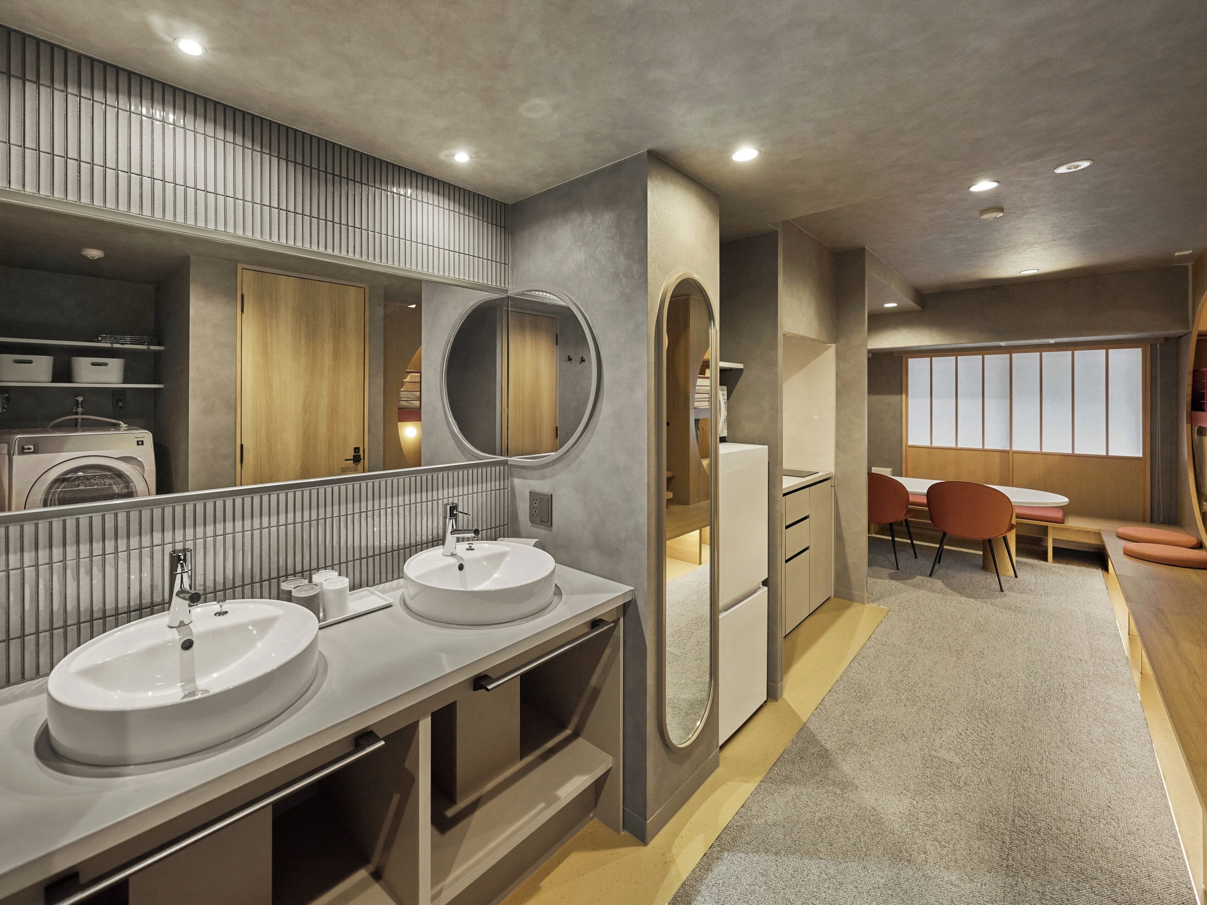 A modern bathroom with dual sinks, a large mirror, and a built-in washing machine.