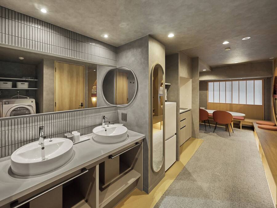A modern bathroom with dual sinks, a large mirror, and a built-in washing machine.