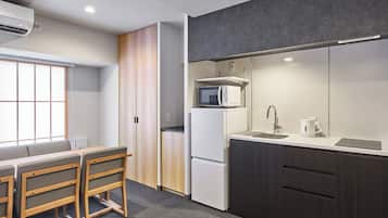 A modern kitchen with a microwave, refrigerator, and sink. There is a dining area with a table and chairs.