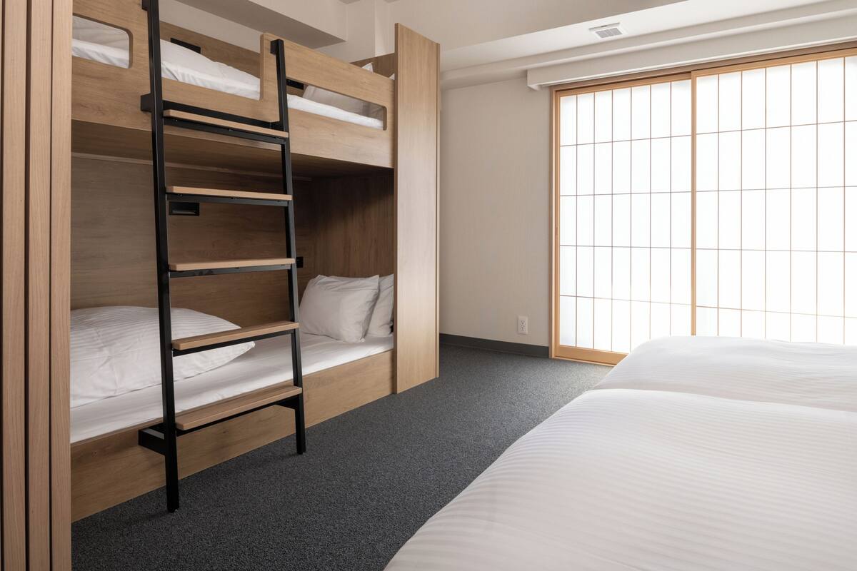 A bunk bed with a ladder, a window with a grid pattern, and an air conditioning unit.