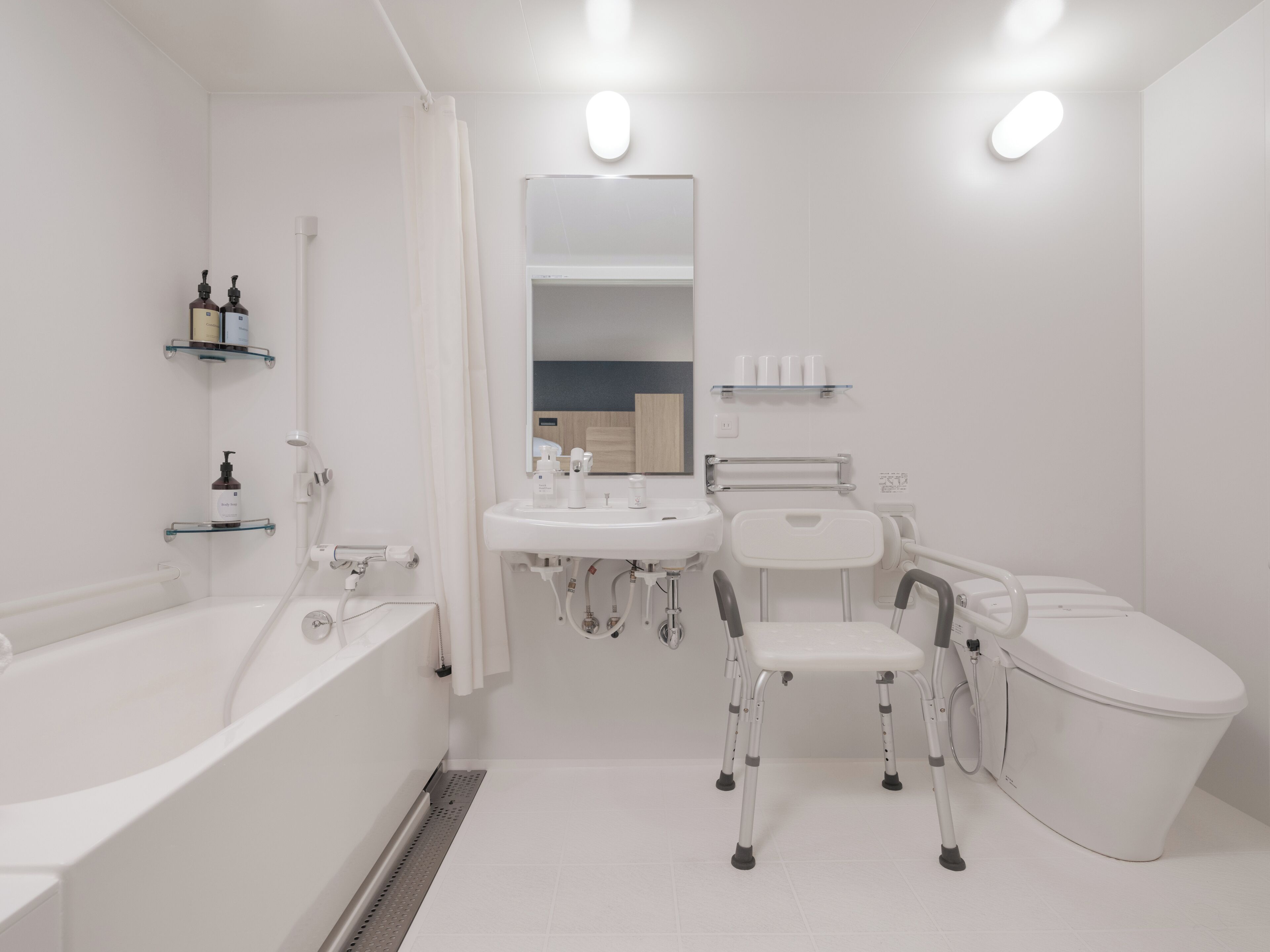 Een moderne badkamer met een badkuip, een wastafel, een toilet en een rolstoel toegankelijke stoel.