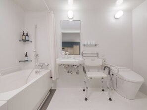 Een moderne badkamer met een badkuip, een wastafel, een toilet en een rolstoel toegankelijke stoel.