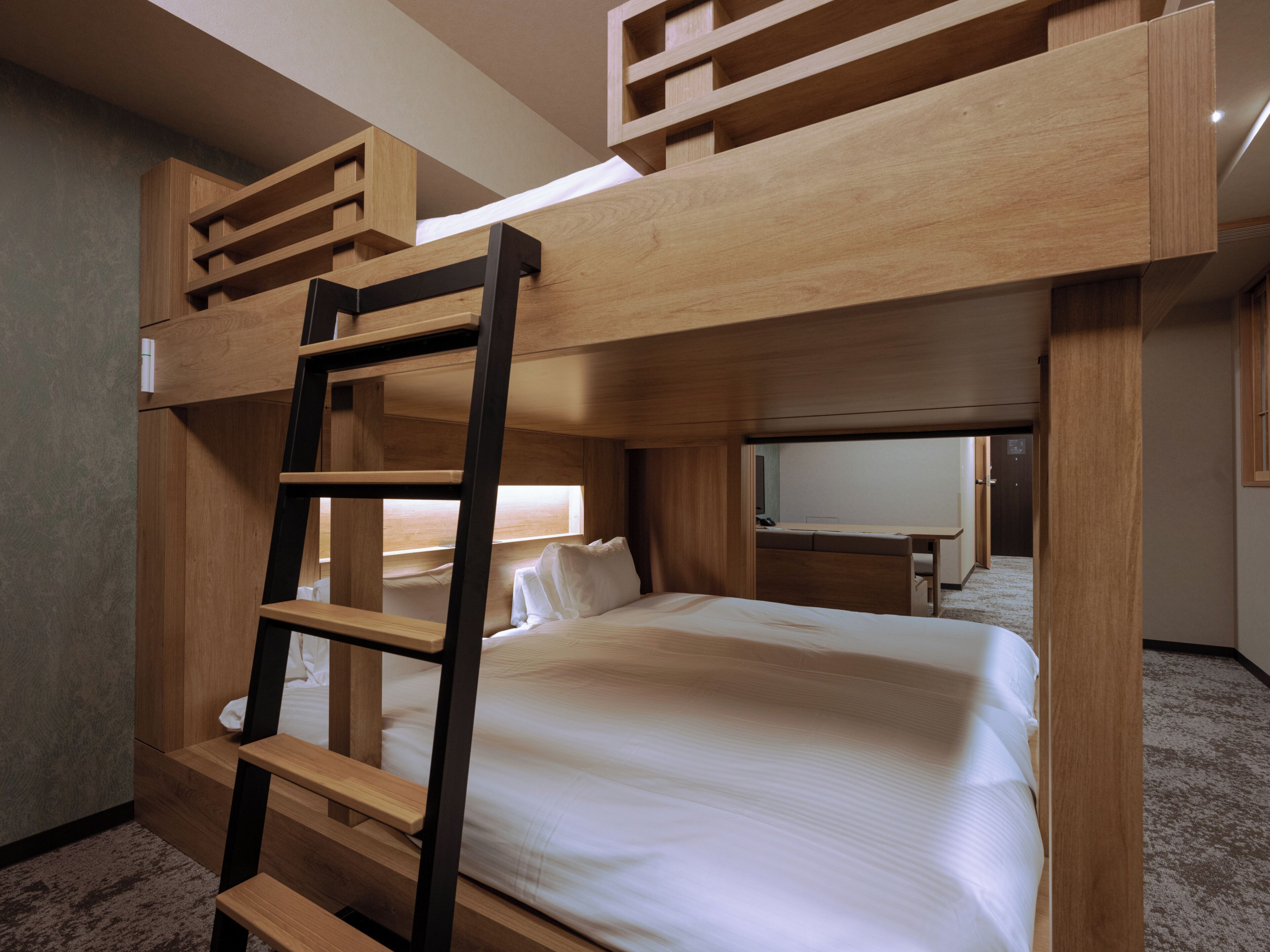 A bunk bed room with a ladder, a desk, and a television in the background.