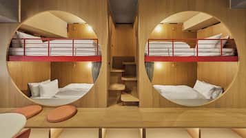 Habitación con literas de diseño circular, paredes de madera y una escalera central.