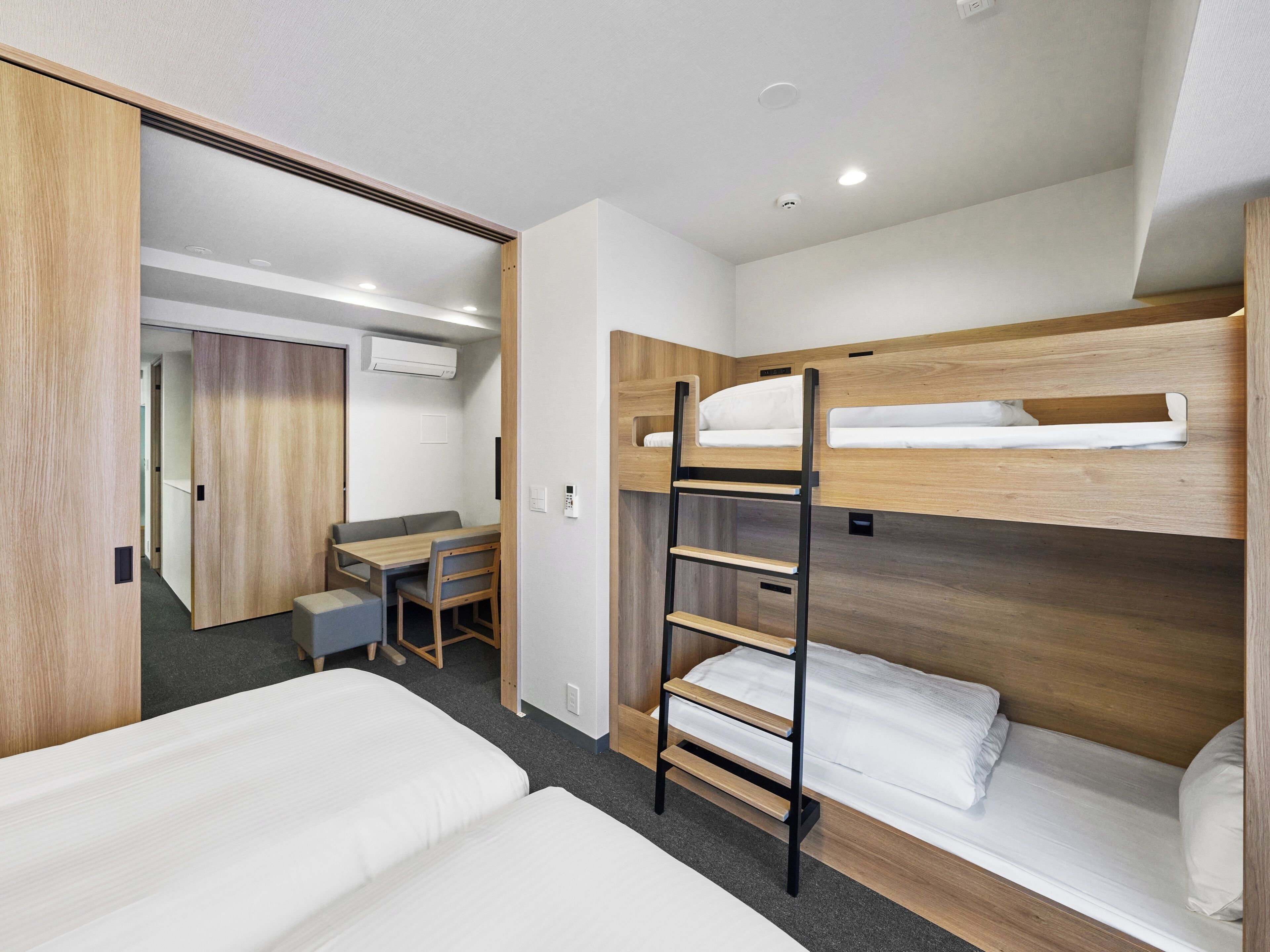 A hotel room with bunk beds, a desk, and a chair.