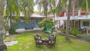 A villa with a stone wall, a swing, and a green pergola. - KNB West Villa Inn by SMS Hospitality (Bolinao)