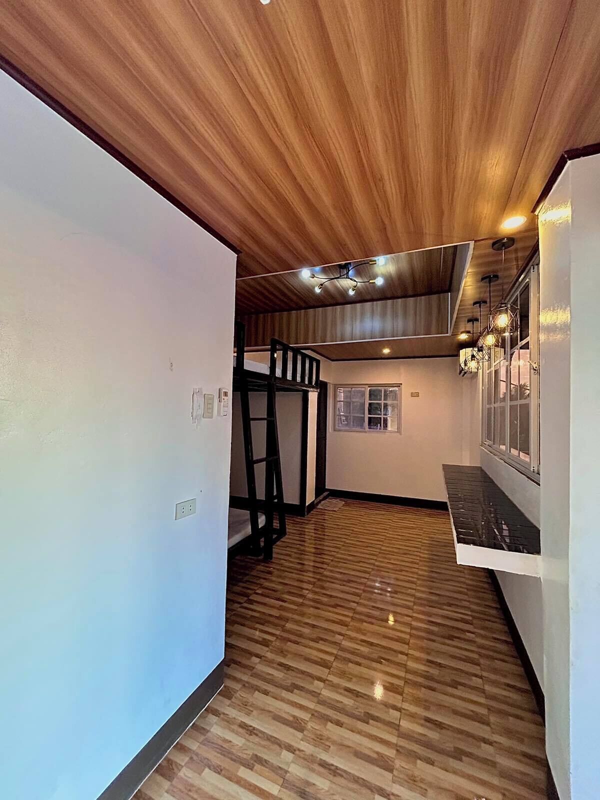 Una habitación con piso de madera, una litera y una ventana con persianas.