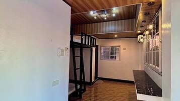 Una habitación con piso de madera, una litera y una ventana con persianas.